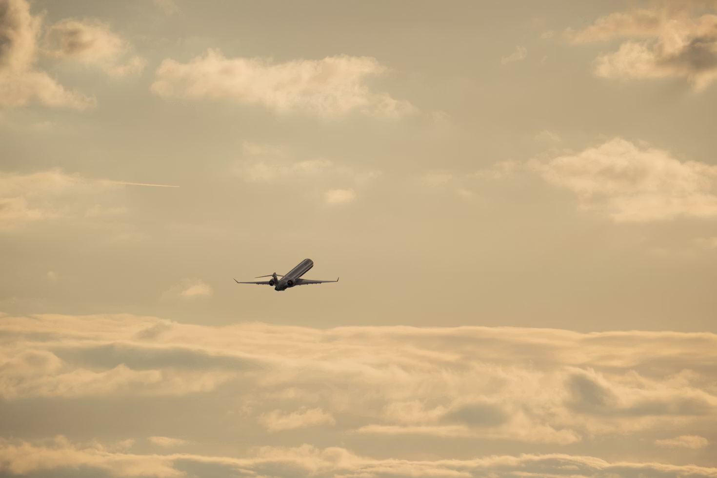 A jet climbing into a golden, cloud-filled sky